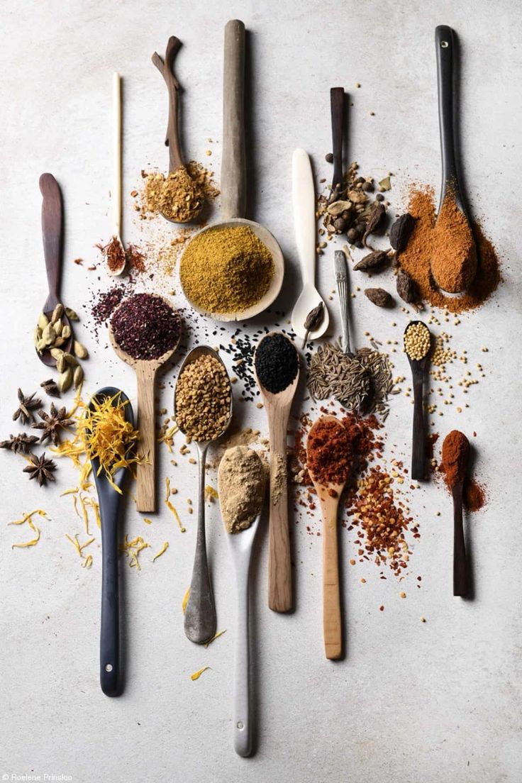 several spoons with different types of spices and seasonings in them on a white surface