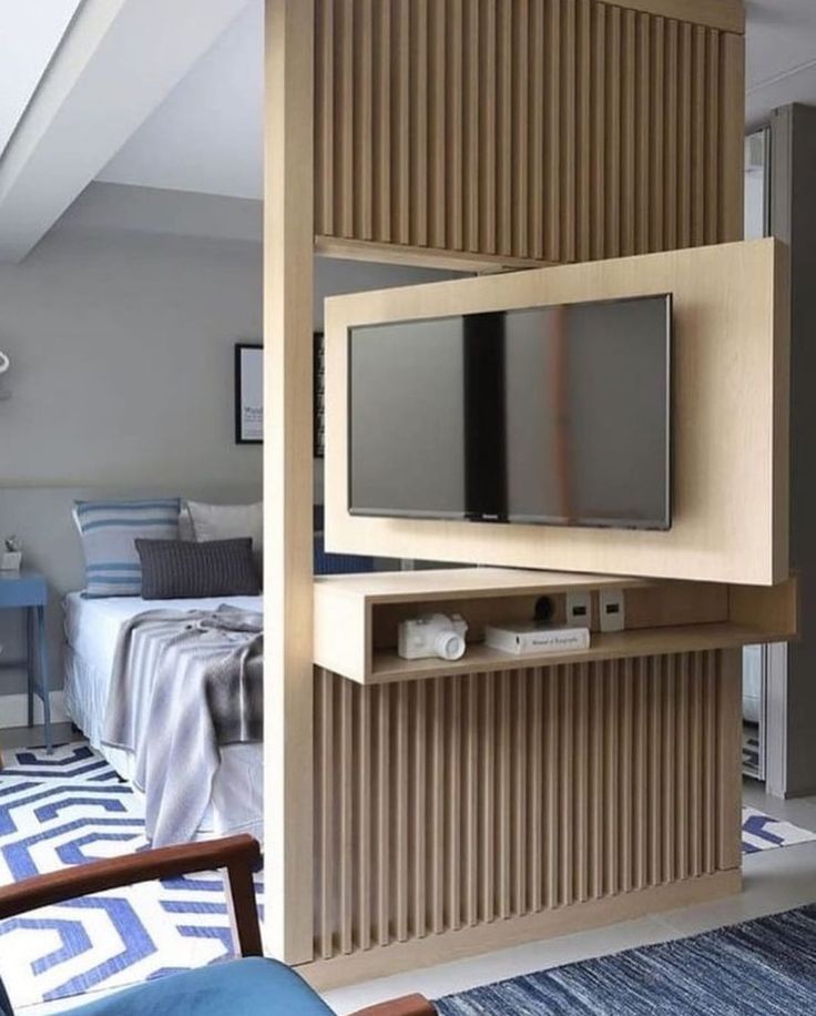 a room with a bed, chair and television on the wall next to each other