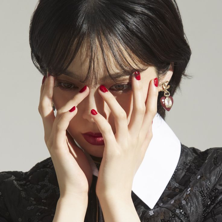 a woman with red nail polish holding her hands to her face and covering her eyes