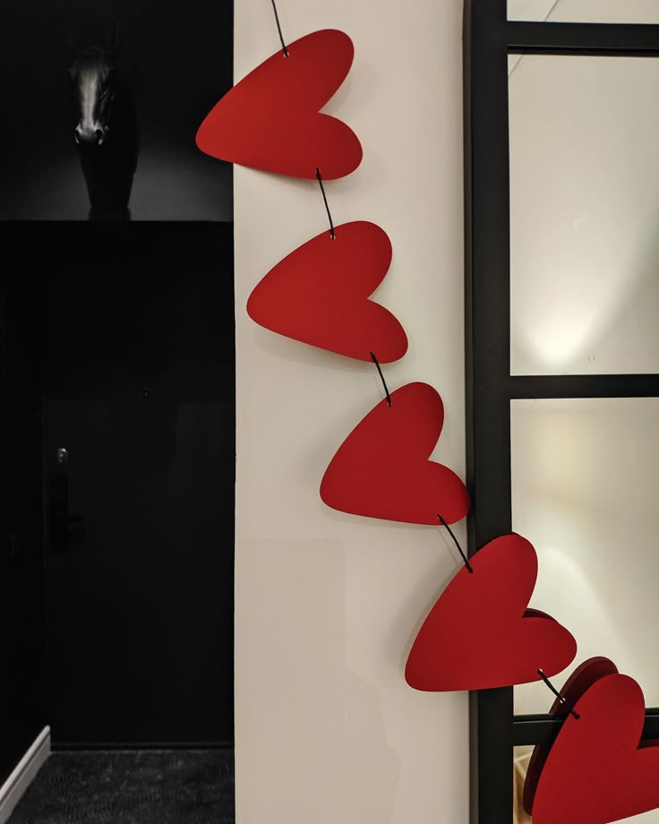 two red hearts hanging from a string on a wall