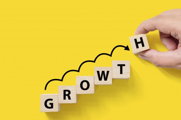 the word growth spelled out with scrabble blocks in front of a person's hand