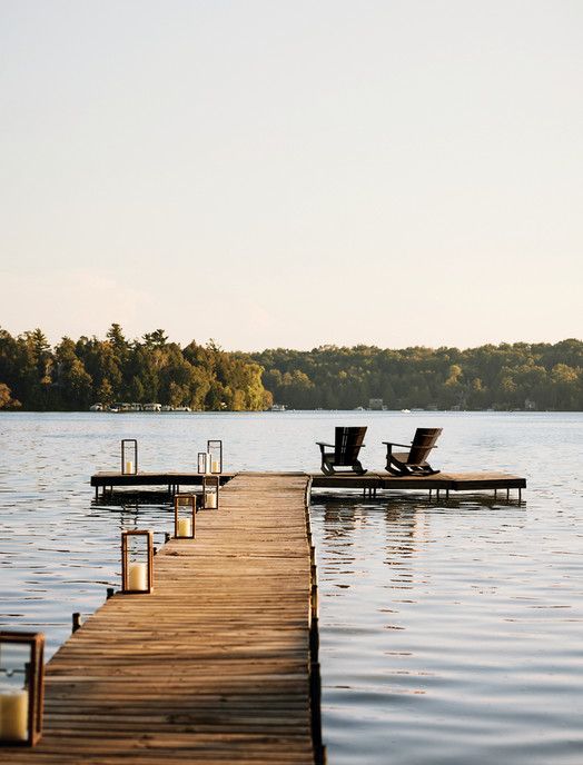 two lounge chairs sitting on top of a wooden dock