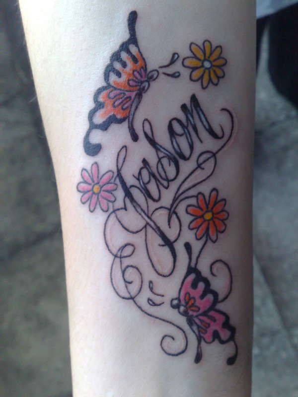 a tattoo with the word mom written on it and flowers in the center, along with two butterflies