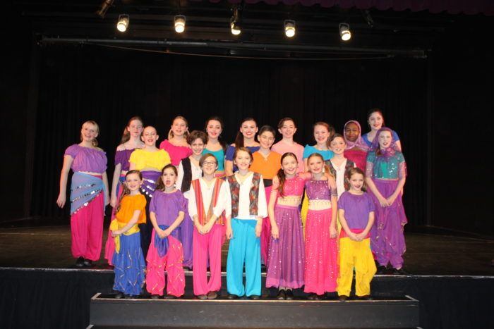 a group of young people standing on top of a stage next to eachother