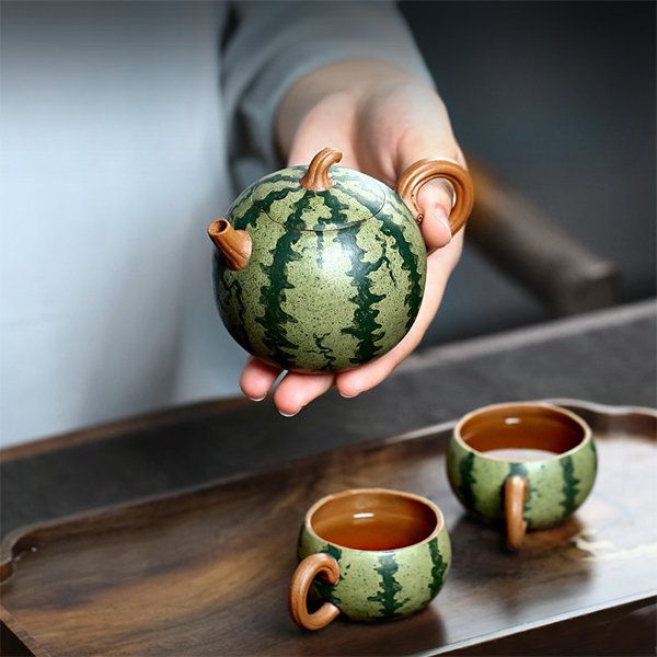 a person holding a teapot and two cups