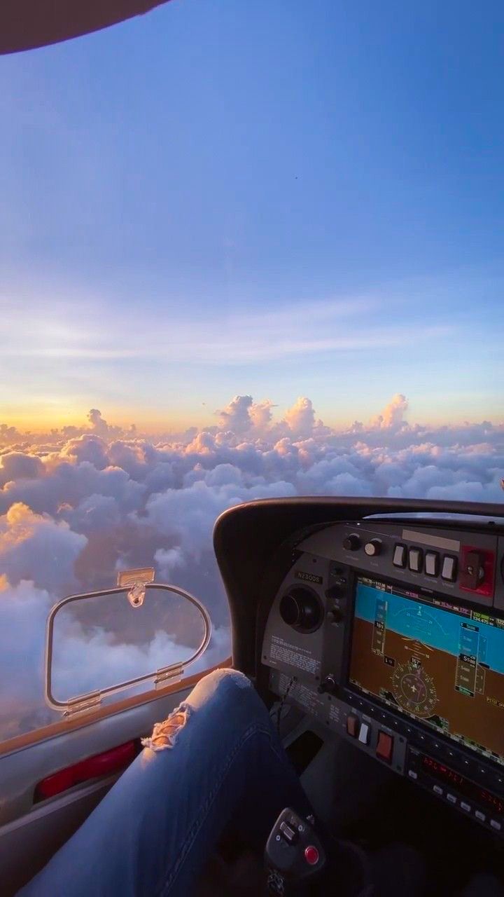 a person sitting in the cockpit of an airplane looking out at the clouds and sky