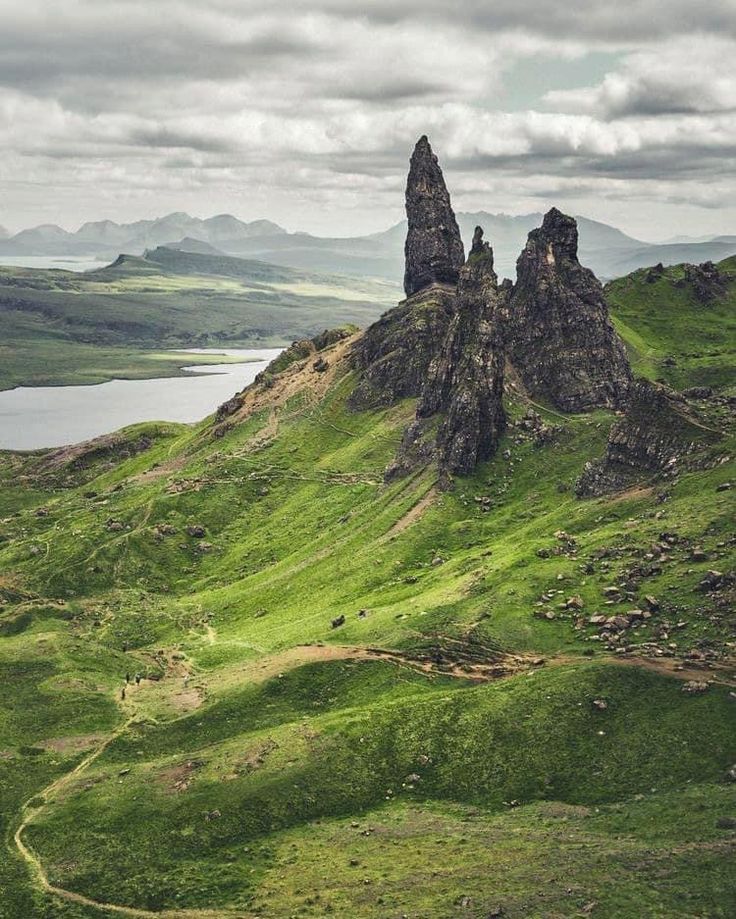 the mountains are covered in green grass and there is a body of water below them