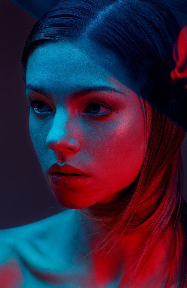 a woman with red and blue light on her face, looking at the camera while she is