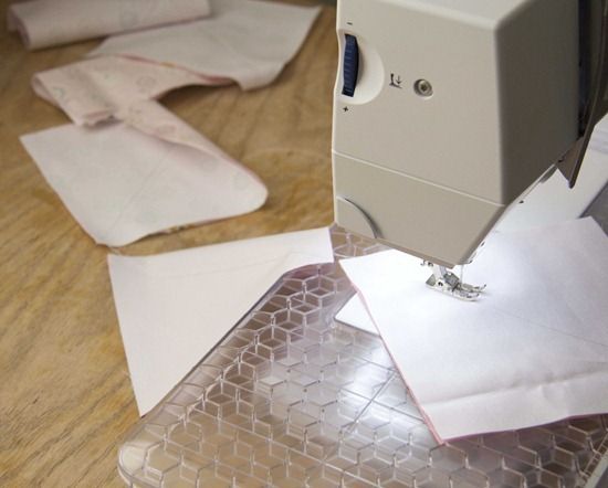 a sewing machine is on top of some white paper and plastic sheets that have been folded over it