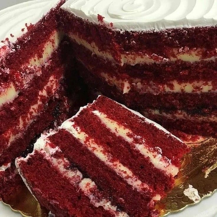 a red velvet cake with white frosting is cut from the plate and ready to be served