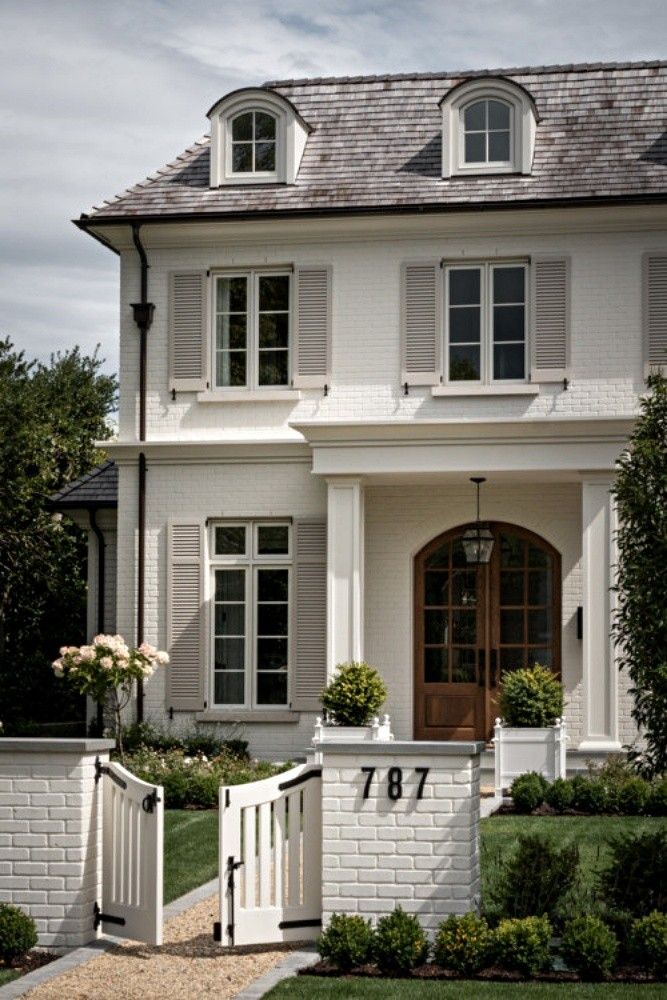 a large white house with two story windows and a gate in front of the entrance