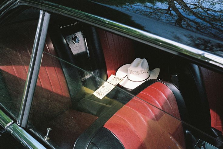 an old car with red seats and a white hat on the dash board in front of it