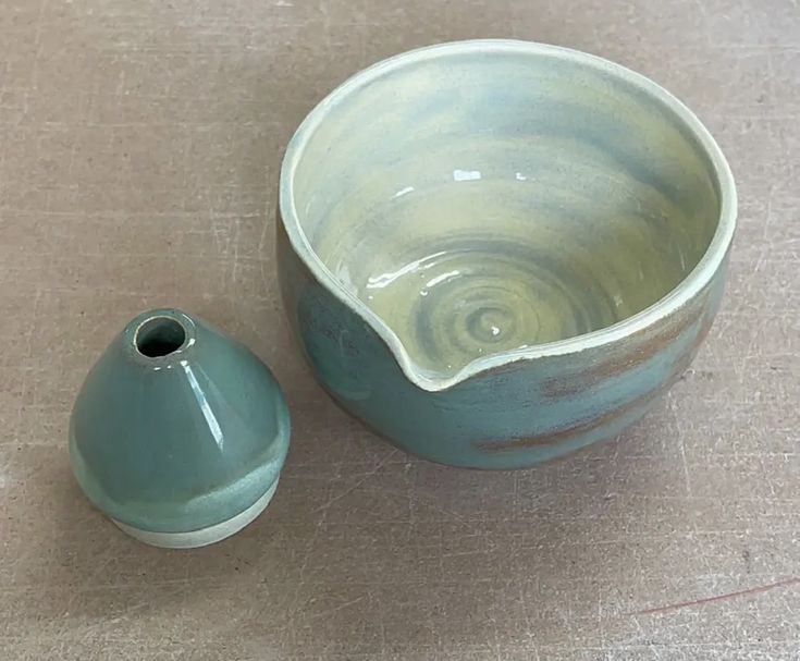 a blue and white bowl sitting next to a ceramic vase