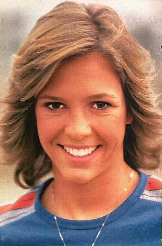 an old photo of a woman with blonde hair and blue shirt smiling at the camera