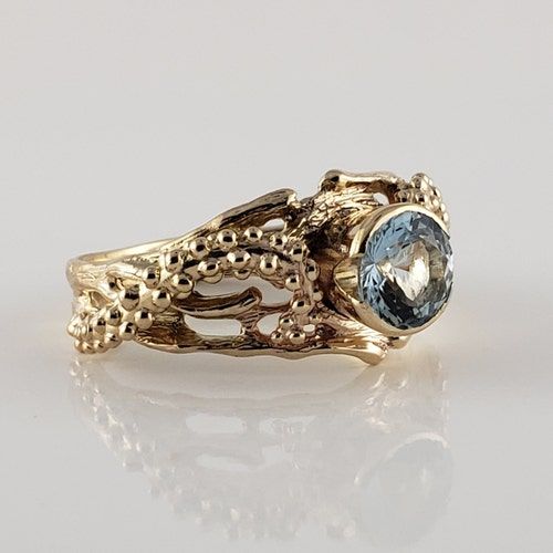 a yellow gold ring with an oval blue topazte and filigrees