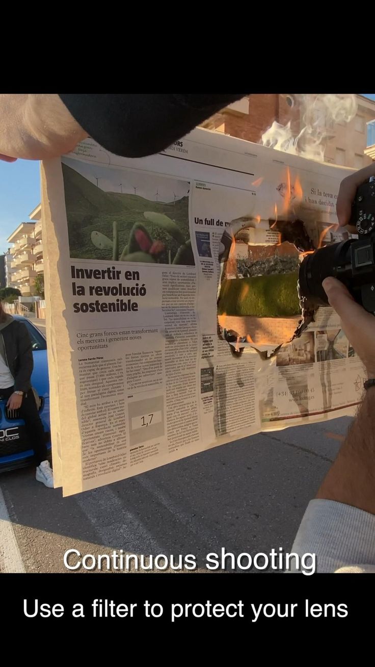 a person holding up a camera in front of a newspaper with the words continuous shooting use a filter to protect your lens