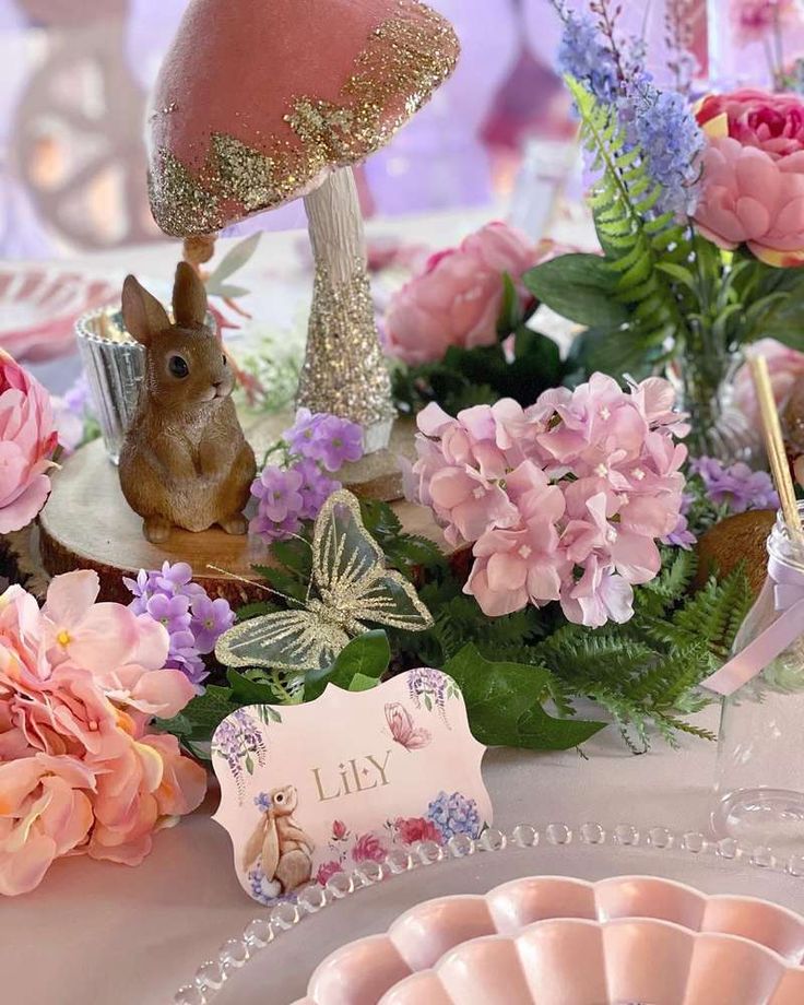 a table topped with lots of pink and purple flowers next to a mushroom shaped object