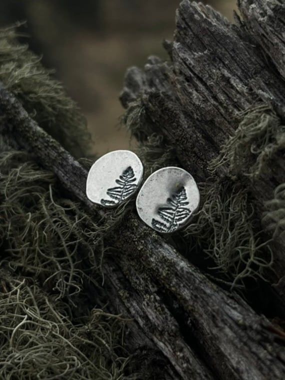 These fern earrings are a stunning testament to the beauty of nature. Each pair of botanical earring features a circle of high-quality silver that's been crafted by melting the silver down into a ball and hammering it flat to create a unique and organic shape. A solid silver earring post is then soldered onto the back of the earring and hardened by hand. Then the Fern design is carefully stamped onto the silver, creating a beautifully detailed and intricate pattern. Inspired by the lush forests Silver Fern, Plant Jewelry, Botanical Earrings, Nature Earrings, Hand Illustration, Organic Shapes, Earring Backs, Jewelry Earrings Studs, Post Earrings