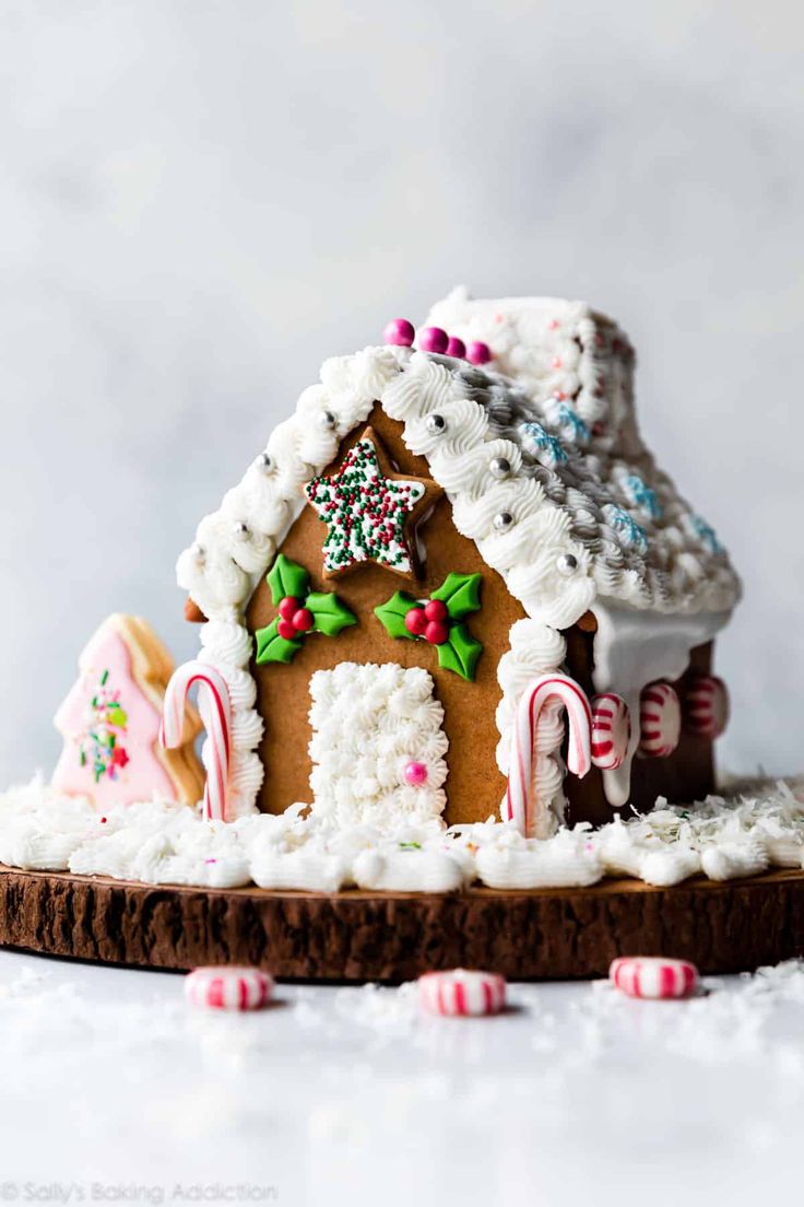 a gingerbread house with candy canes and candies on the side, sitting on top of a piece of wood