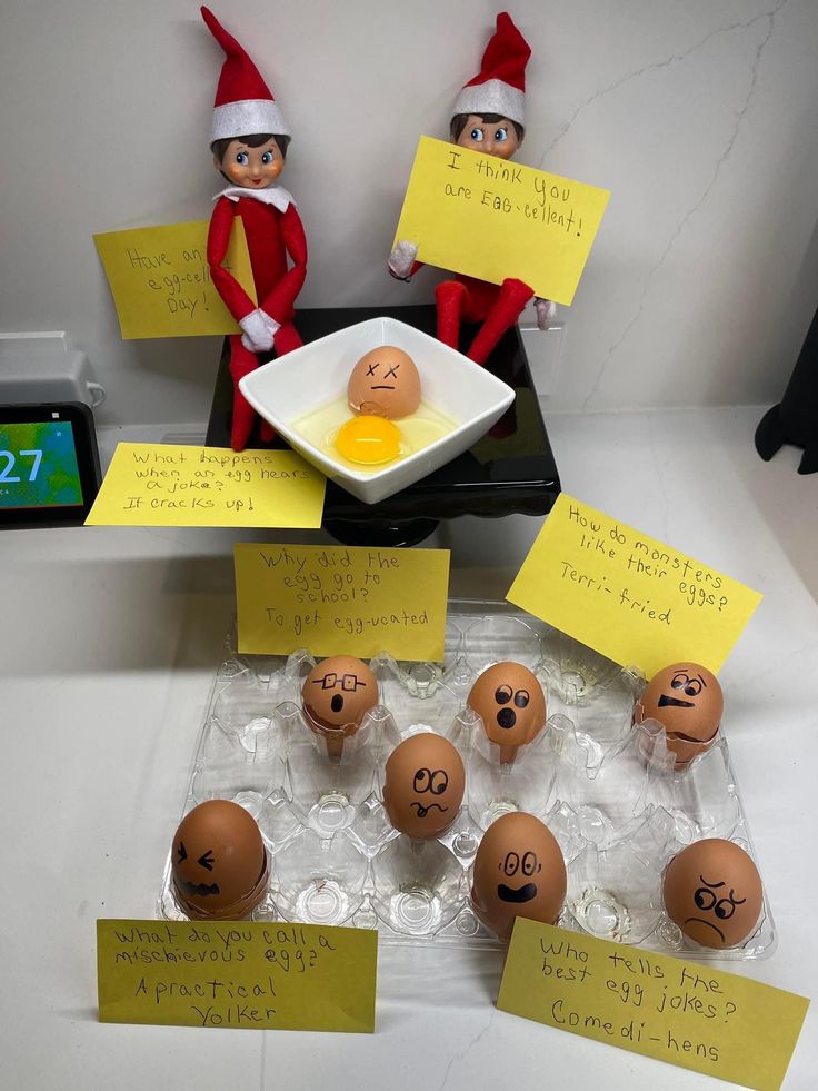 two elfs are sitting in front of eggs with faces drawn on them and sticky notes