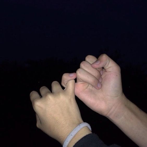 two hands holding each other in the dark