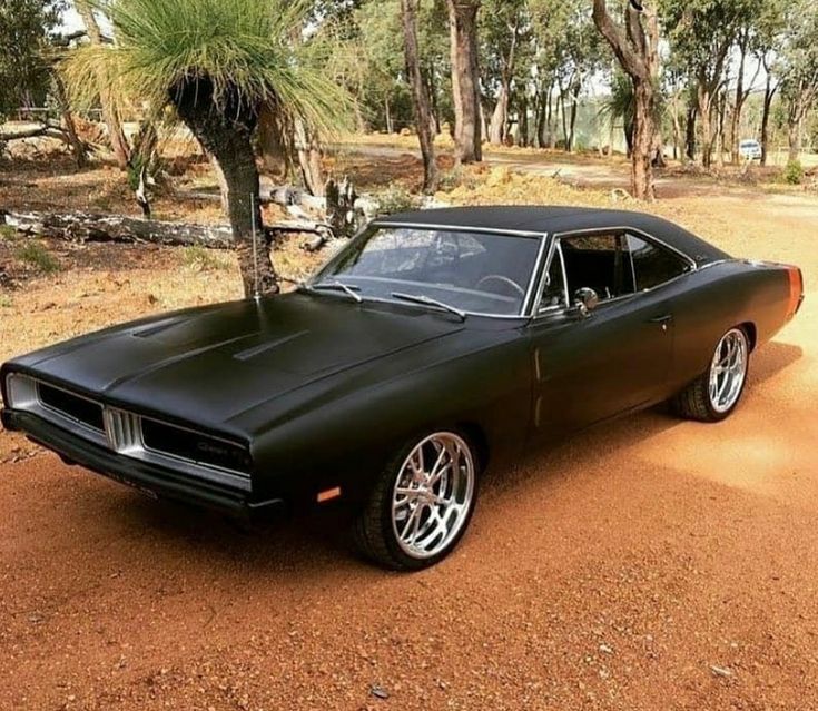 a black muscle car parked in the dirt