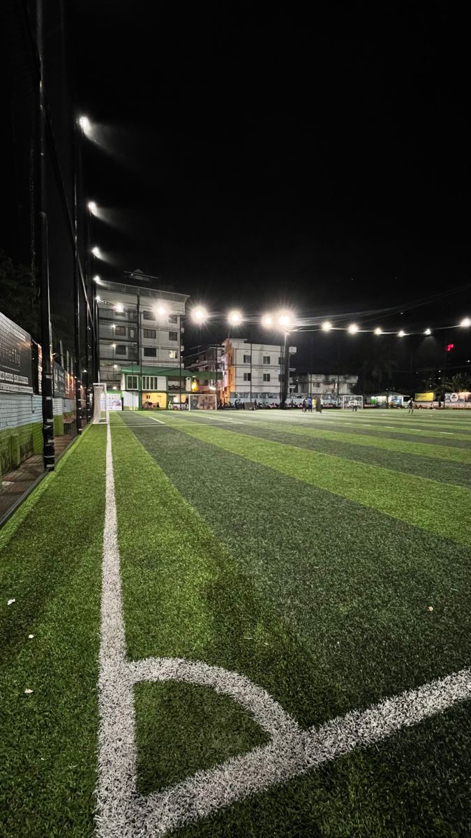 an empty baseball field at night with lights on the stands and grass in the outfield