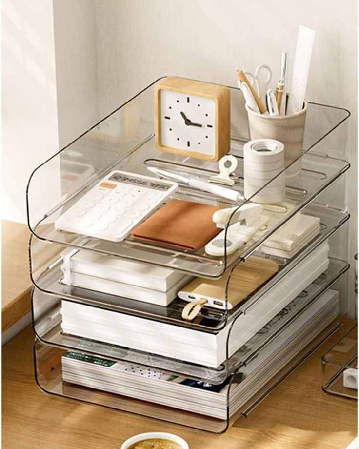 a stack of books on a desk with a clock and pen holder in the corner