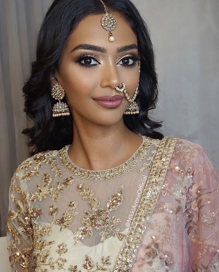 a woman in a bridal outfit with gold jewelry on her face and nose piercings