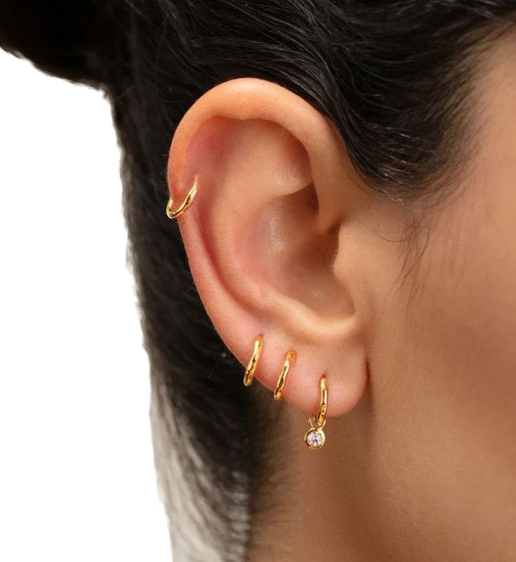 a close up of a person's ear with two small gold rings on it