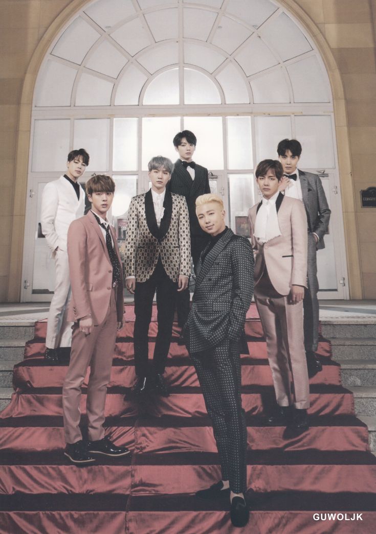 a group of young men standing on top of a red carpeted floor next to each other