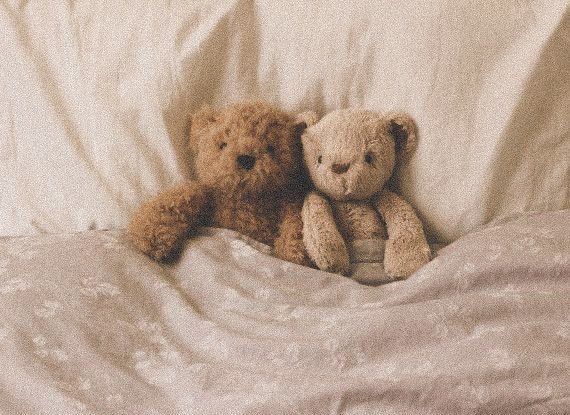 two teddy bears sitting on top of a bed