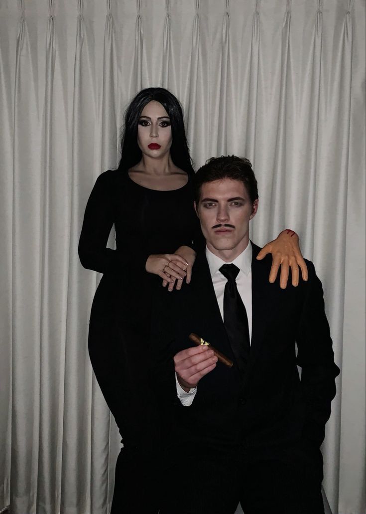 a man and woman dressed in black standing next to each other with hands on their chest