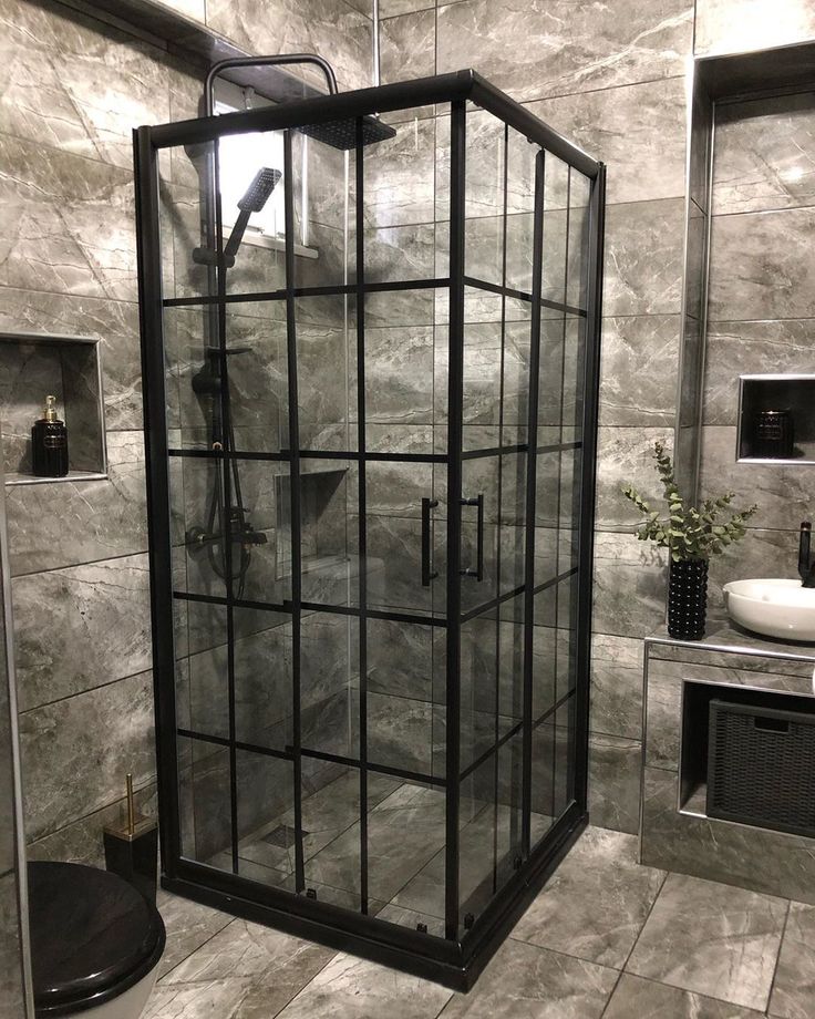 a glass enclosed shower in a bathroom with tile flooring and walls, along with a black standup shower head