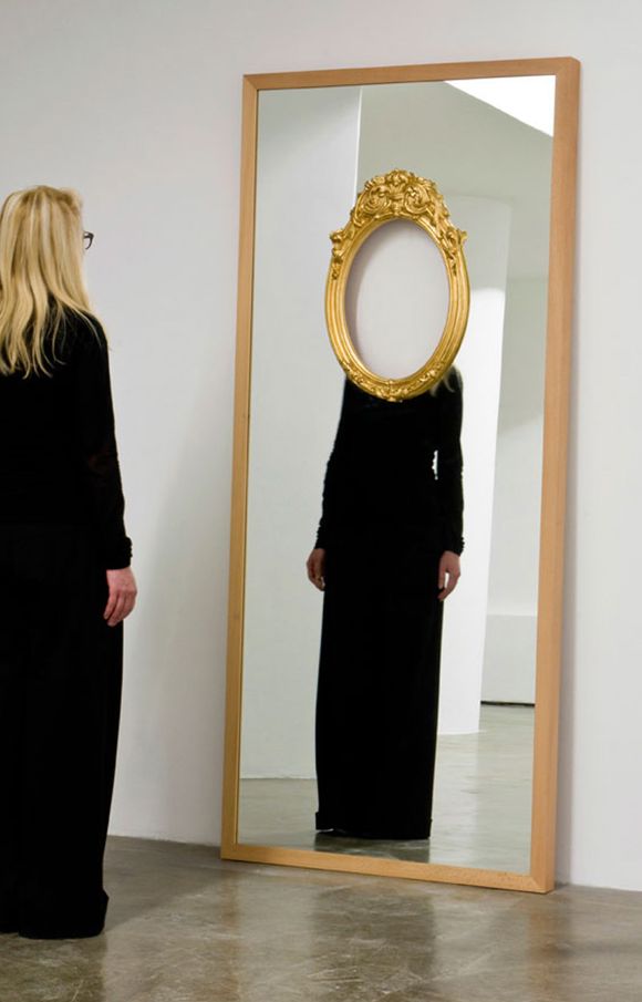 a woman standing in front of a mirror looking at her reflection wearing a black dress