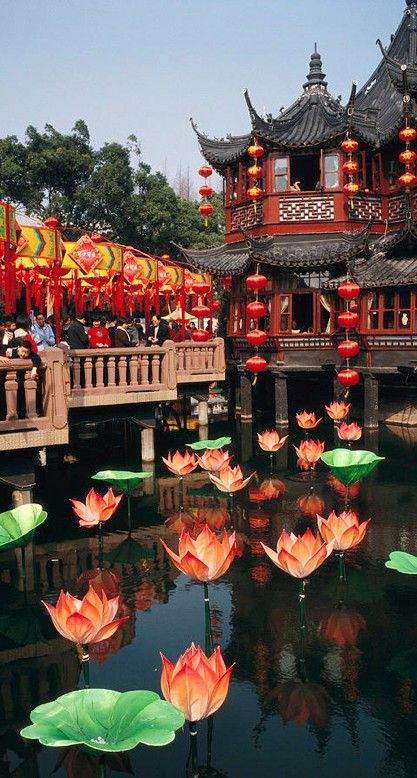 there are many water lilies floating in the pond and people standing on the bridge