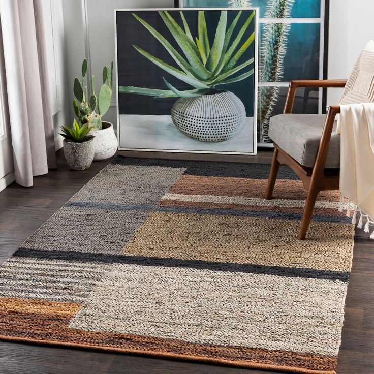 a living room area with a rug, chair and potted plant on the floor