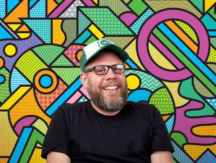 a man sitting in front of a colorful wall