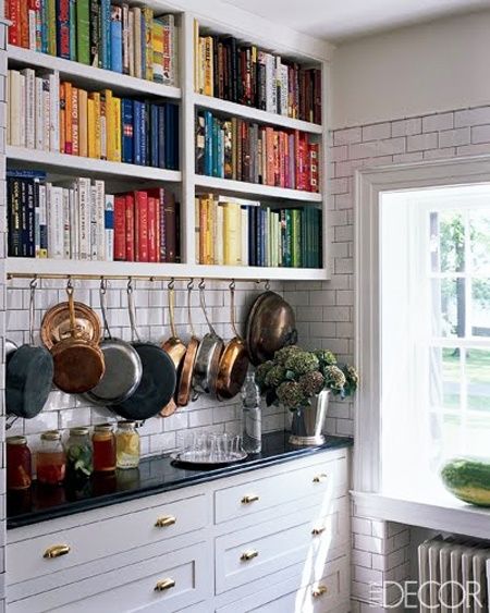 a kitchen with bookshelves filled with cookbooks and cooking utensils