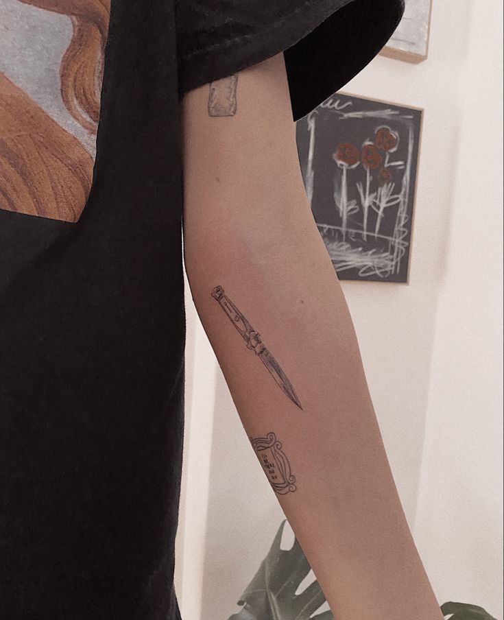 a person with a knife tattoo on their arm