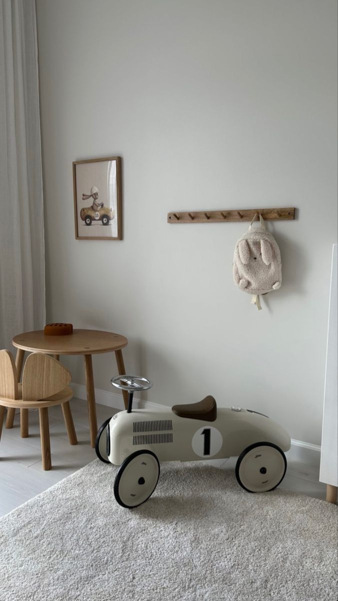 a toy car sitting on top of a white rug next to a wooden table and chair