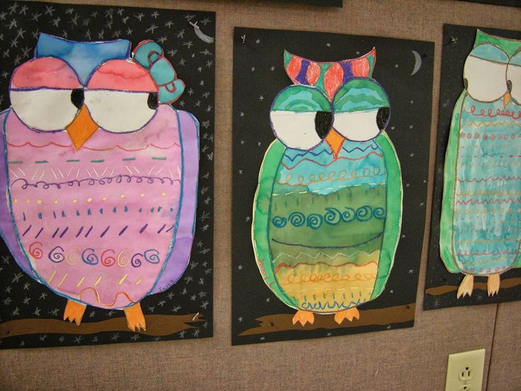 three owl paintings are hanging on the wall in an art class or school classroom room