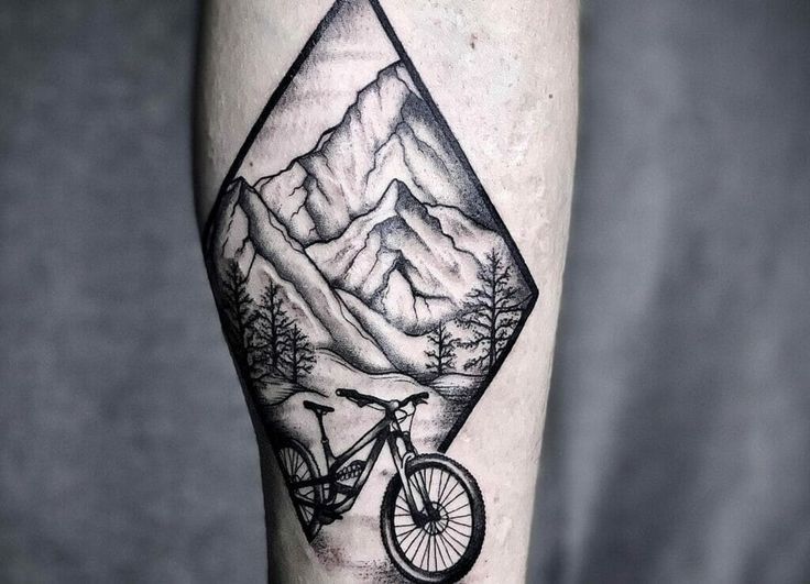 a man's leg with a mountain and bicycle tattoo on it