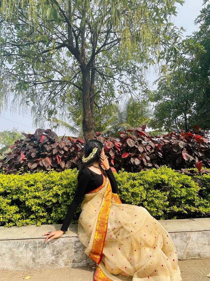 a woman sitting on the ground talking on her cell phone while wearing a sari