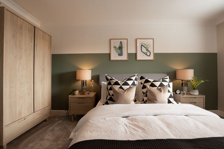 a bedroom with green walls and white bedding, two framed pictures on the wall