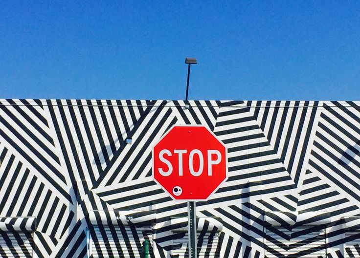 a red stop sign sitting on the side of a black and white striped wall next to a street light