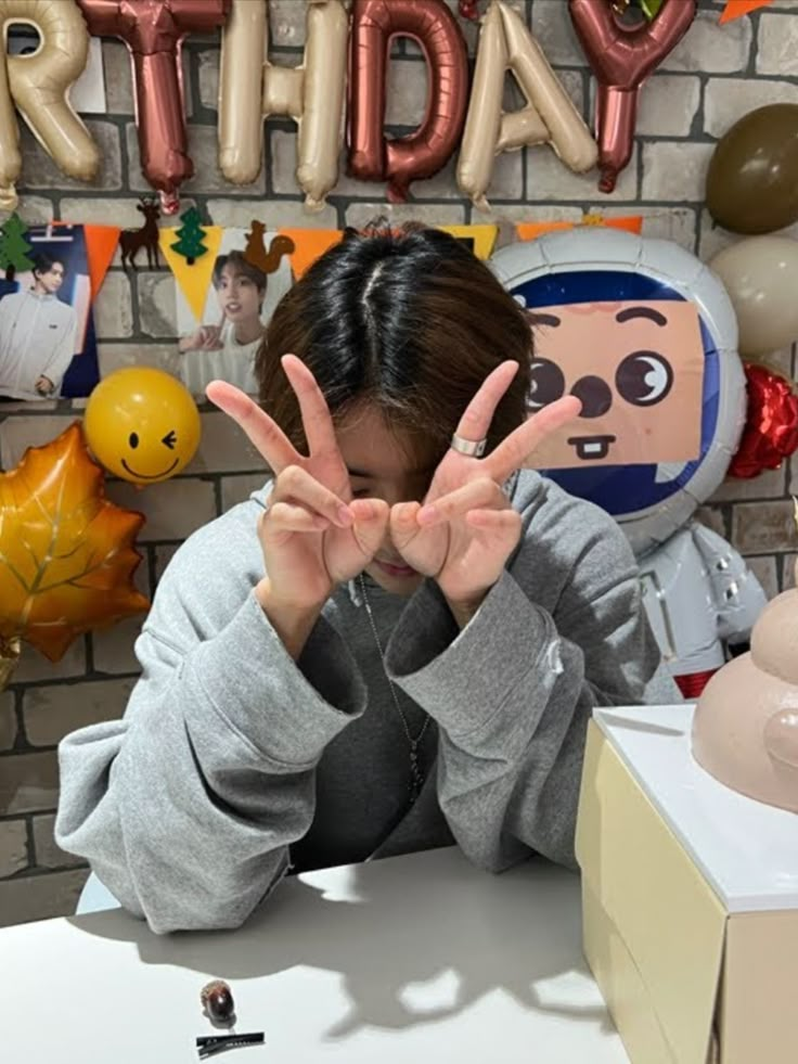 a person sitting at a table with their hands up in front of them, making the peace sign