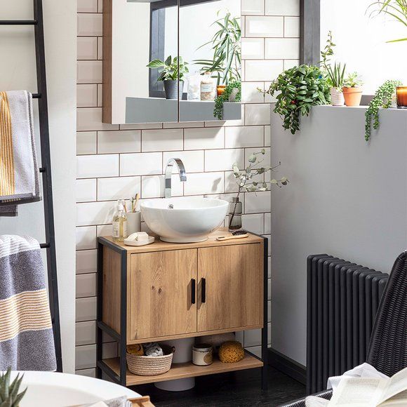 a bathroom with a sink and mirror next to a towel rack, potted plants