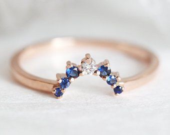 a diamond and blue sapphire ring sitting on top of a white cloth