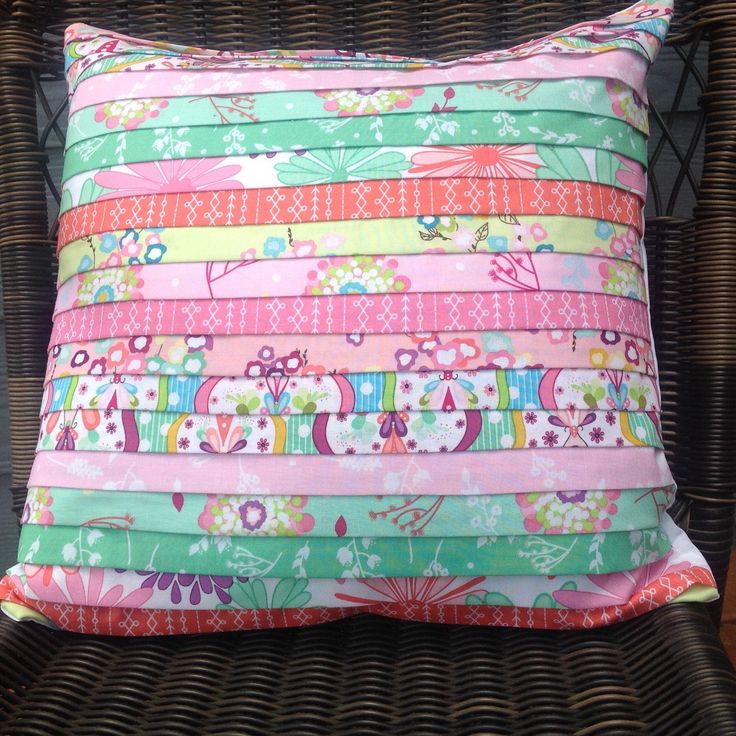 a colorful pillow sitting on top of a wicker chair